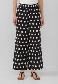 Culottes noirs avec de grands pois blancs, en tissu texturé. Dotés d'une taille élastique et de jambes larges et fluides.