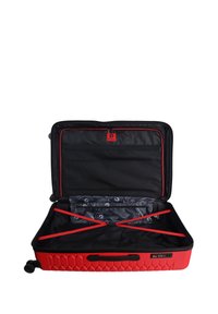 Red hard-shell suitcase with honeycomb texture, black interior lining, zippered pocket, adjustable straps, and combination lock.