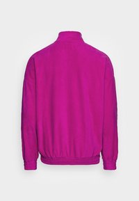 Giacca a pullover fucsia con colletto alto, vita elasticizzata e maniche lunghe. Texture liscia senza hardware o motivi visibili.