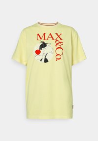 Camiseta de algodón amarilla claro con un gráfico de Sylvester el gato en negro y rojo con el texto "MAX & Co.", cuello redondo y mangas cortas.