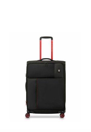 Black soft-shell upright suitcase with red handle and red-accented wheels, front zip pocket, and carry handle on top.