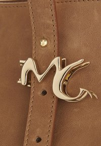 Borsa a mano in pelle marrone con un logo in metallo dorato. Presenta dettagli cuciti e una chiusura a borchie vicino al logo. Texture liscia.