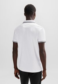 Hvit polo skjorte med kontrasterende svart kant på kragen og ermene, med en myk tekstur og rett hemdesign.