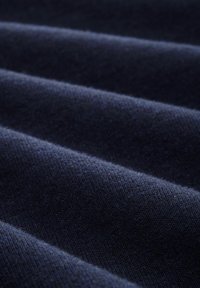 Tessuto blu navy con una superficie morbida e testurizzata e pieghe visibili, che mette in mostra un motivo tessuto e uno spessore uniforme.