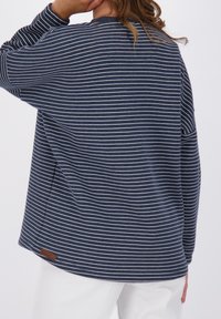 Top a righe navy con maniche lunghe, caratterizzato da strisce orizzontali bianche, realizzato in un tessuto morbido, con collo rotondo e un piccolo etichetta marrone all'orlo.