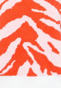 Maglione lavorato a maglia con un motivo a strisce tigre rosse e rosa, realizzato in tessuto morbido con orlo a coste bianco.