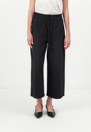 Zwarte, wijde broek met een elastische tailleband en trekkoord. Gemaakt van zachte stof, met zijzakken en een ontspannen pasvorm.