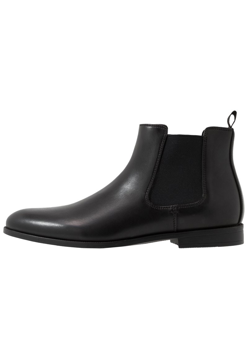 Botte chelsea en cuir noir dotée de panneaux latéraux élastiques, d'une finition lisse et d'une languette au talon. Talon bas avec un design minimaliste.