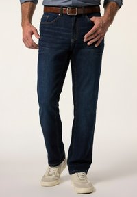 Mörkblå denimjeans med rak benpassform, med subtila slitningar och klassisk femfickdesign, parat med vita sneakers.