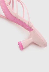 Roze hoge hakken met een slank ontwerp. Bandjes bovenkant, gestructureerde zool en een gedurfde blokhak met een roze accent aan de basis. Gladde afwerking.
