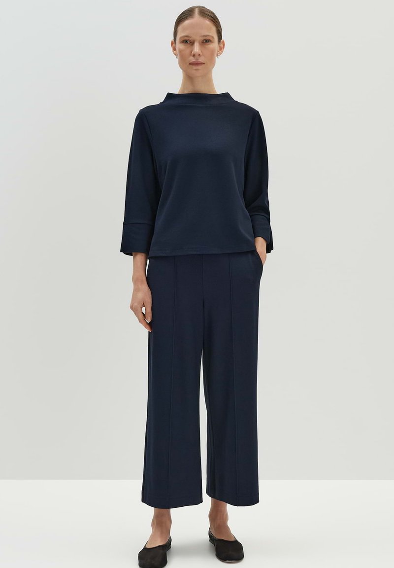 Haut bleu marine avec un col haut et des manches trois-quarts, associé à un pantalon large assorti, tous deux en texture lisse.