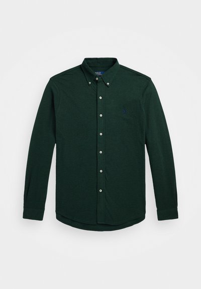 Mørkegrønn langermet skjorte med knapper laget av myk stoff, med spiss krage, frontknapper og en liten brodert logo.