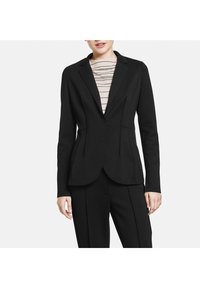 Blazer noir sur mesure avec une coupe structurée, doté d'un col cranté, de détails de coutures discrètes et d'une texture de tissu lisse.