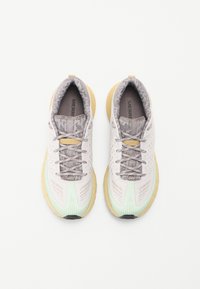 Baskets légères avec un dessus en mesh dans des tons de rose pastel et de menthe, accents gris texturés et semelle rembourrée jaune. Comprend un système de laçage.