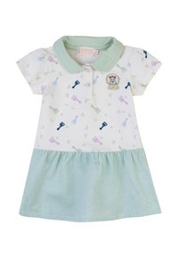 Abito polo a maniche corte bianco con motivi di giraffe pastello, colletto verde e gonna a righe verdi. Presenta bottoni e un distintivo di leone.