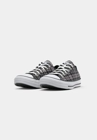 Sneakers in tela grigia a quadri con suole e dettagli in gomma bianca, dotati di lacci bianchi e un design a bassa cima. Suola nera con motivo di trazione.