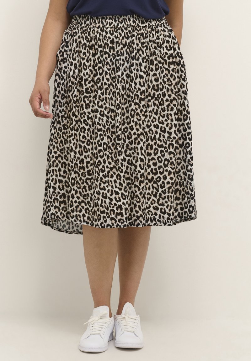 Luipaardprint midi-rok met plooien, elastische tailleband en een vloeiende stof; gecombineerd met witte sneakers voor een casual look.