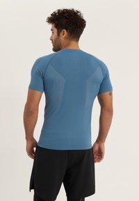 Fitted blue athletic shirt with short sleeves, featuring a textured pattern of small holes across the back and shoulders for ventilation.