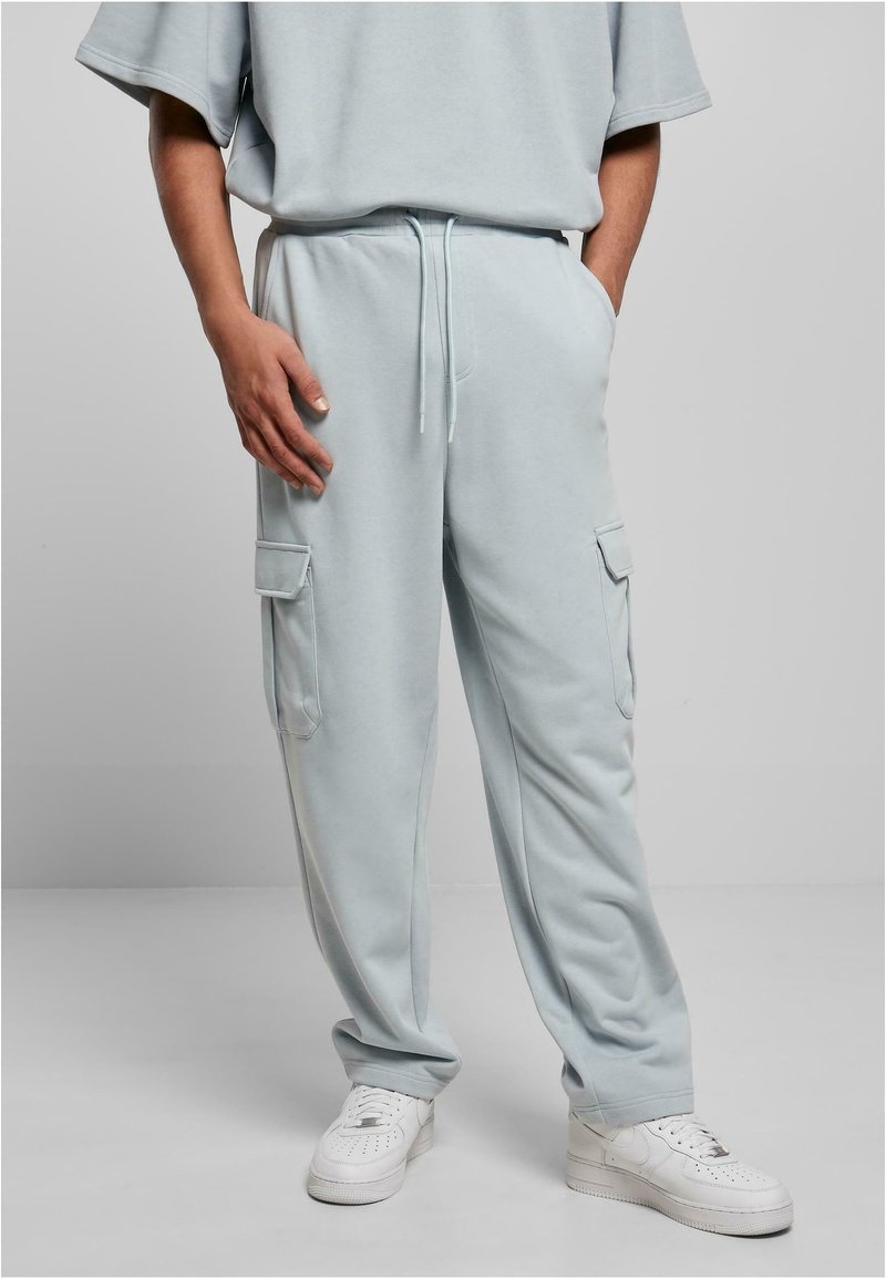 Light blue cotton joggers with side cargo pockets, elastic waistband, and drawstring. Paired with white sneakers. Smooth texture.