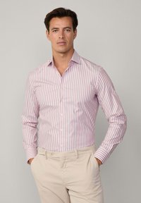 Camicia a righe rosa chiaro e bianca in tessuto di cotone, con colletto a punta e chiusura a bottoni, abbinata a pantaloni beige.