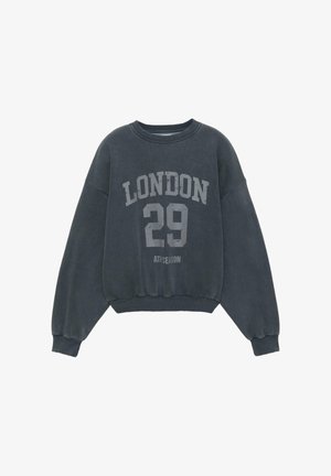 Donkergrijze trui met een ronde hals, doorgezakte schouders en geribbelde manchetten. Heeft de opdruk "LONDON 29" en "ATH SEASON" in lichtgrijs.