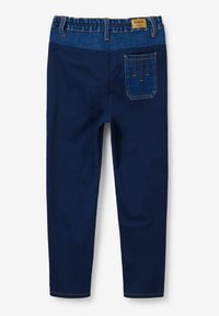 Pantalones azul marino hechos de un material suave con una cinturilla de estilo denim, que cuentan con un bolsillo trasero con costuras en contraste y una etiqueta.