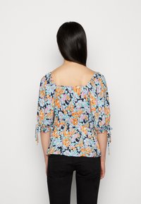 Blusa floral com decote quadrado, mangas curtas bufantes, cintura ajustada, flores vibrantes laranja e azuis sobre um fundo escuro, tecido leve.