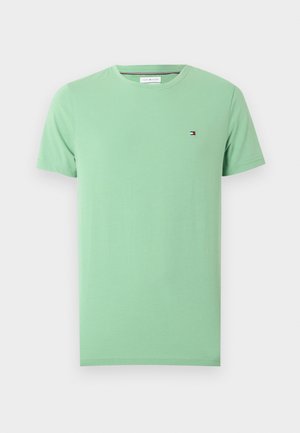 T-shirt vert clair à manches courtes et col rond avec un petit logo rouge, blanc et bleu brodé sur la poitrine gauche.
