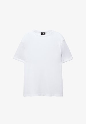 Vit bomull t-shirt med korta ärmar, rund halsringning och avslappnad passform. Slät textur utan mönster eller dekorationer.