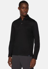 Czarna, długosleeve'owa koszulka polo z gładkiej bawełny. Posiada kołnierzyk, zapięcie na trzy guziki oraz subtelne logo na dolnym brzegu.