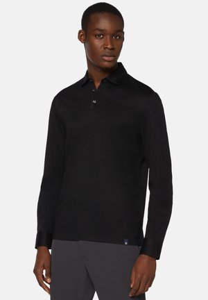 Schwarz langärmliges Polohemd aus glattem Baumwollstoff. Verfügt über einen Kragen, eine Dreiknopf-Leiste und dezente Branding am Saum.