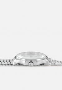 Sølvmetal ur med rund urskive, armbånd i rustfrit stål og klart glas. Har en fremtrædende krone og minimalistisk urskivedesign.
