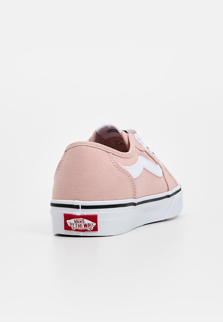 Zapatilla de lona rosa de caña baja con franja lateral blanca y suela media negra. Cuenta con un logo rojo de "Vans Off the Wall" en el talón.