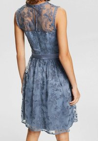 Vestido azul con bordados florales, espalda transparente, corsé ajustado y falda acampanada con cinturilla de satén.