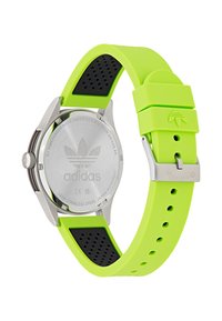 Sportig klocka med ett hus av rostfritt stål, ett klart grönt silikonarmband, svarta detaljer och en logotyp ingraverad på baksidan. Vattentålig upp till 5 ATM.