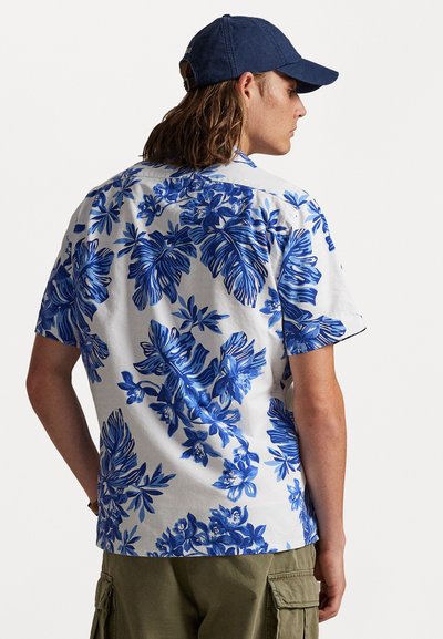 Κοντομάνικο πουκάμισο από ελαφρύ ύφασμα με μπλε λουλουδάτο μοτίβο. Ο σχεδιασμός περιλαμβάνει μεγάλα φύλλα και λουλούδια, με κλασικό γιακά.