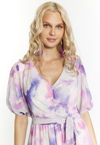 Rochie cu imprimeu floral în culori pastelate (roz, mov, albastru), cu decolteu în V, mâneci bufante și o talie legată, având butoane decorative.