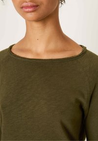 Olive green long-sleeve shirt with a relaxed fit. Features a wide, unfinished neckline and textured fabric with visible stitching at edges.