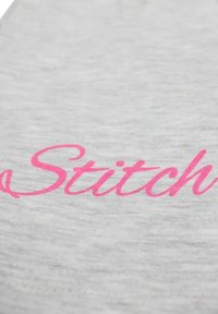 Tissu gris avec le mot « Stitch » en cursive rose vif et en gras. La texture est douce et lisse, avec un léger ombrage sur toute la matière.