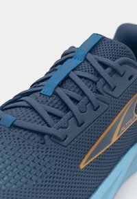 Baskets de course en mesh bleu avec une surface texturée, des œillets renforcés et un logo contrastant orange et bleu sur le côté.