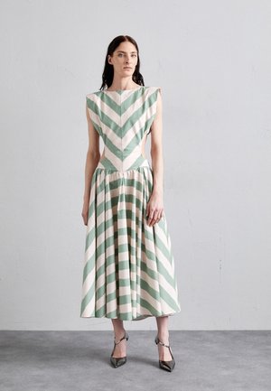 Robe rayée avec des chevrons verts et rose clair alternés, sans manches, et jupe évasée. Tissu lisse avec des découpes sur les côtés.