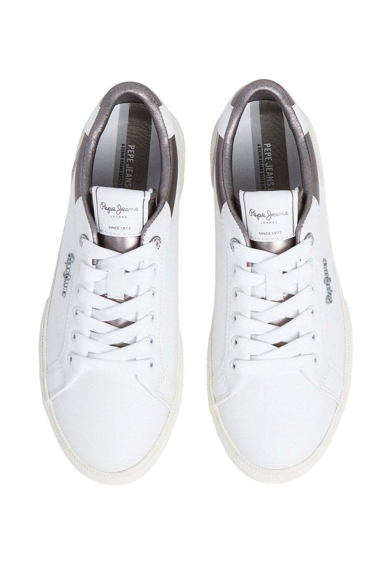 Baskets blanches avec une tige en cuir lisse, fermeture à lacets et un accent gris au talon. Présente un patch logo sur la languette.