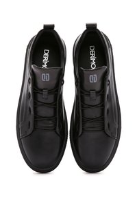 Zapatillas negras con una textura de cuero suave, que presentan un diseño de perfil bajo, cordones y una lengüeta acolchada con detalles del logotipo.