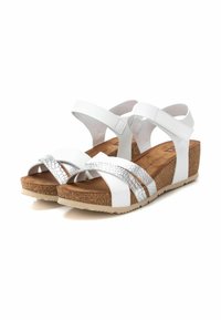Sandalias blancas con cuña y suela de corcho. Presentan tiras cruzadas ajustables y un acento texturizado en plata en la parte superior. Suela antideslizante.