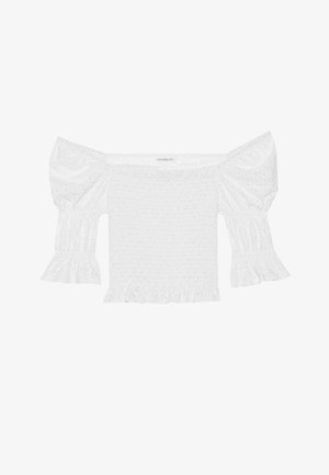 Bela off-shoulder majica s napuhanim rukavima, smučenim korpusom i raširenim volanom. Izrađena je od teksturirane pamuka s ukrasima od čipke.