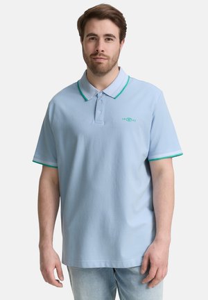 Lys blå polo skjorte med grønne detaljer på kraven og ærmerne. Har en tre-knaps knaplukning og broderet logo på brystet.