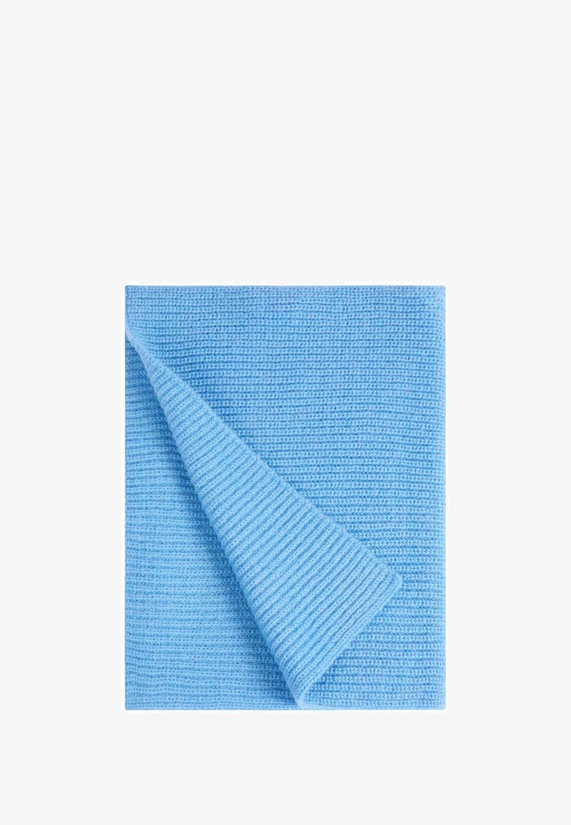 Coperta blu, texture a coste, parzialmente piegata per rivelare il suo morbido tessuto intrecciato. Finitura liscia, design leggero.