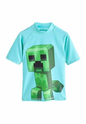 Rashguard à manches courtes, turquoise, présentant un grand graphique d'un Creeper vert de Minecraft sur le devant. Fabriqué en tissu respirant et extensible.