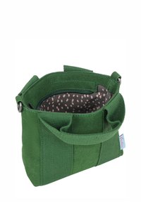 Bolsa de tela verde con un exterior texturizado, dos bolsillos laterales y un interior con cremallera que presenta un forro de lunares rosas. Incluye un asa.