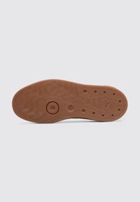 Suela de zapato de goma con una textura ondulada, patrones circulares y ovalados, y un color marrón con ligeras motas para agarre y tracción.